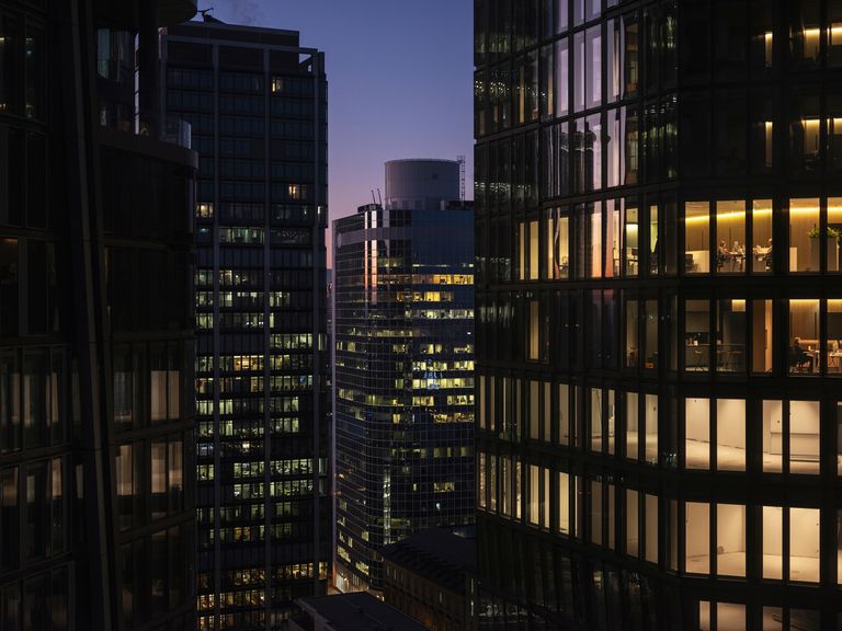 A woman in front of a window watches the city at night  