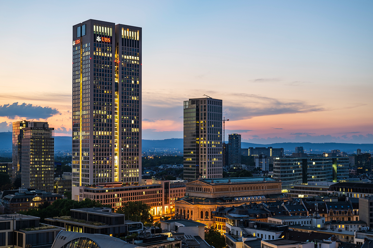 Frau vor Fenster genießt den Ausblick ihrer Luxuswohnung in Frankfurt