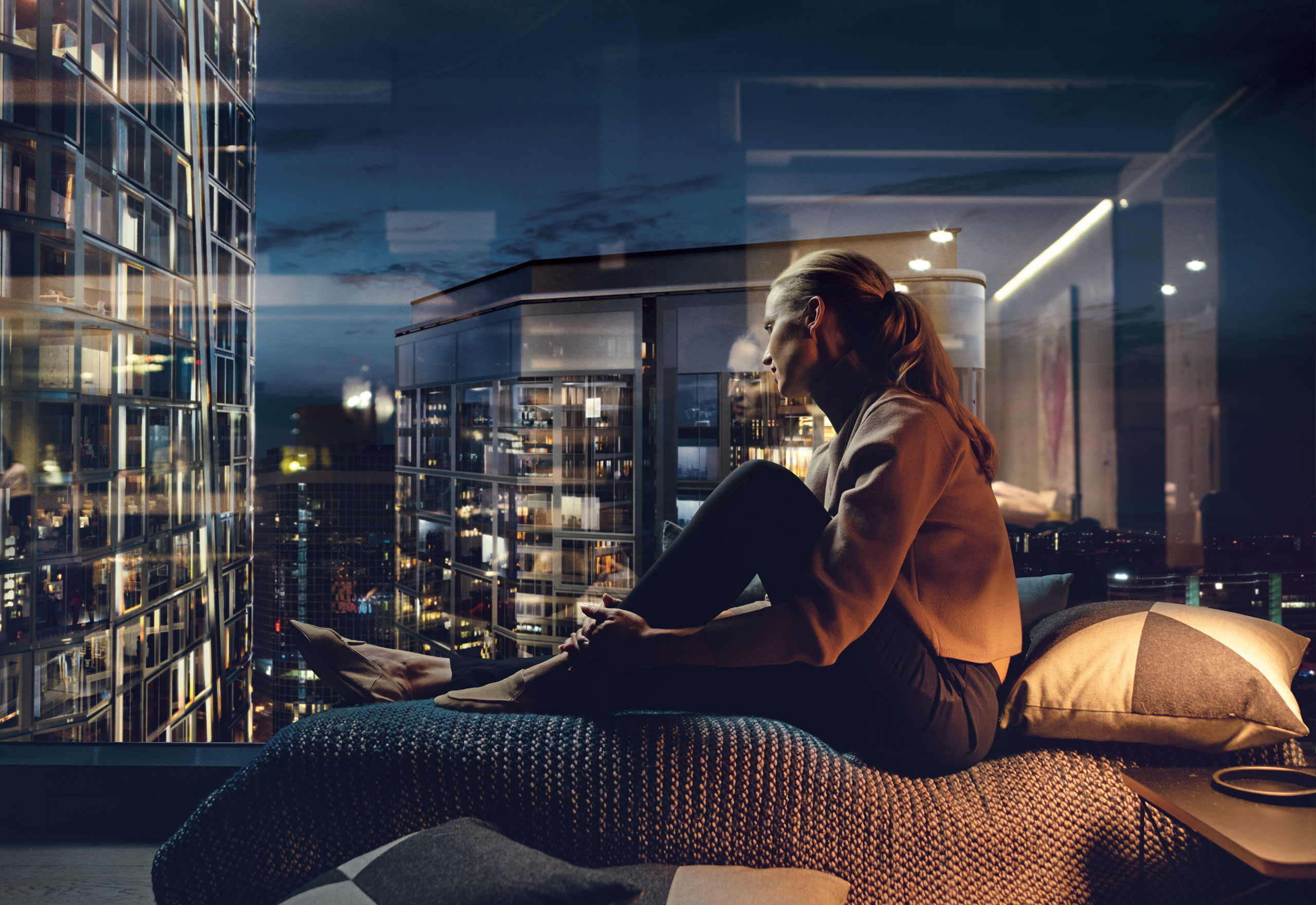 Woman sitting in front of a window admiring the city lights